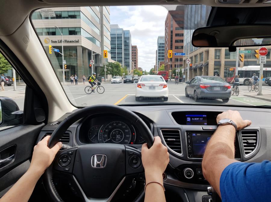 Student driver cautiously approaching a signalized intersection in city traffic